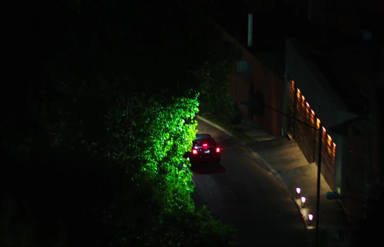 A woman greets a man and gets into her car which leaves the city and from above a woman with a sad expression watches