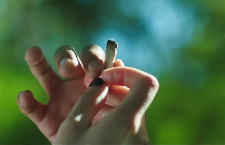 Hands of a woman handing a young girl a cigarette