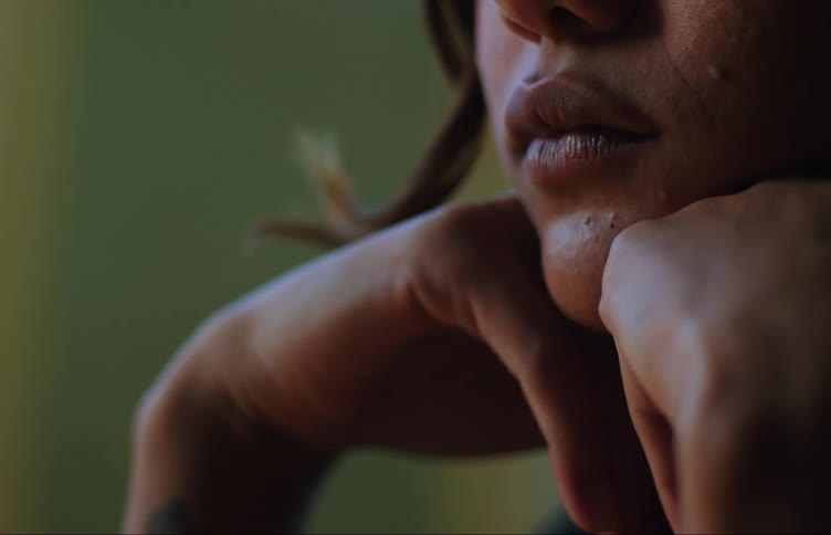 Closeup of the lower face of a young woman with both hands on her chin