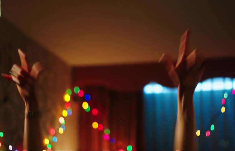 Two teenage girls dancing in a dimly lit room with colorful lights