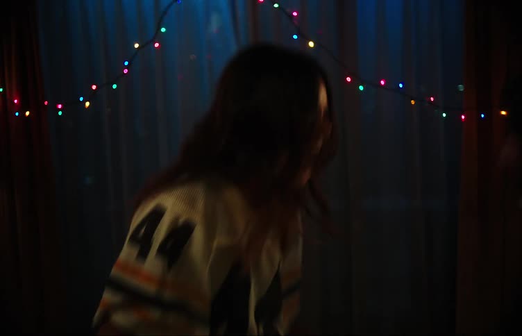 Two teenage girls dancing in a dimly lit room with colorful lights