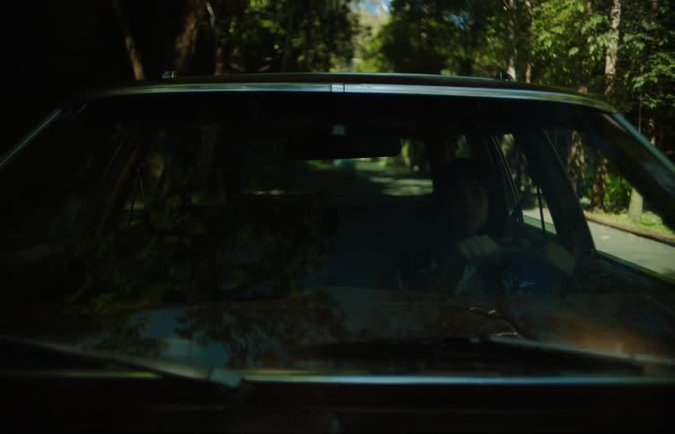 Teenage girl drives a car on the neighborhood while a friend sleeps