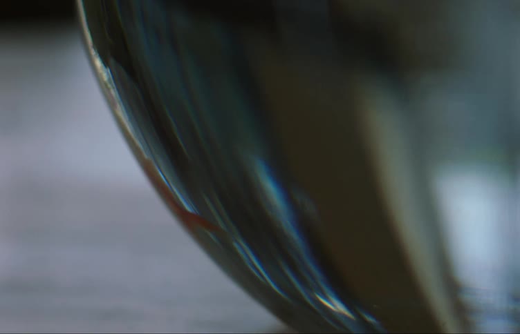 Small goldfish swims in glass bowl on flat surface