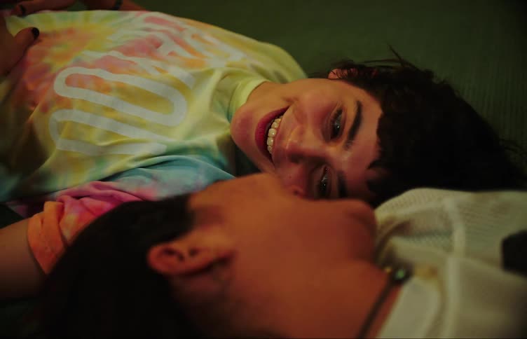 Two young women lying on the carpet looking at each other with an expression of happiness and romance