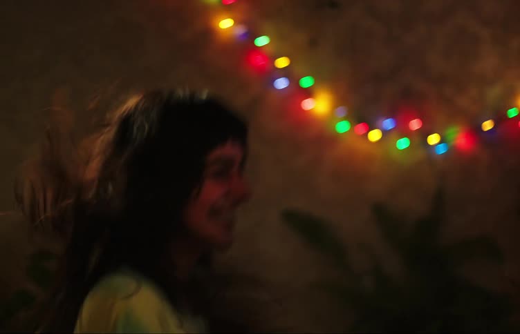 Teenage friends dancing together in a living room at night