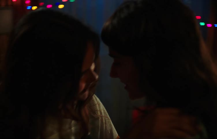 Two teenage girls dancing in a dimly lit room with colorful lights