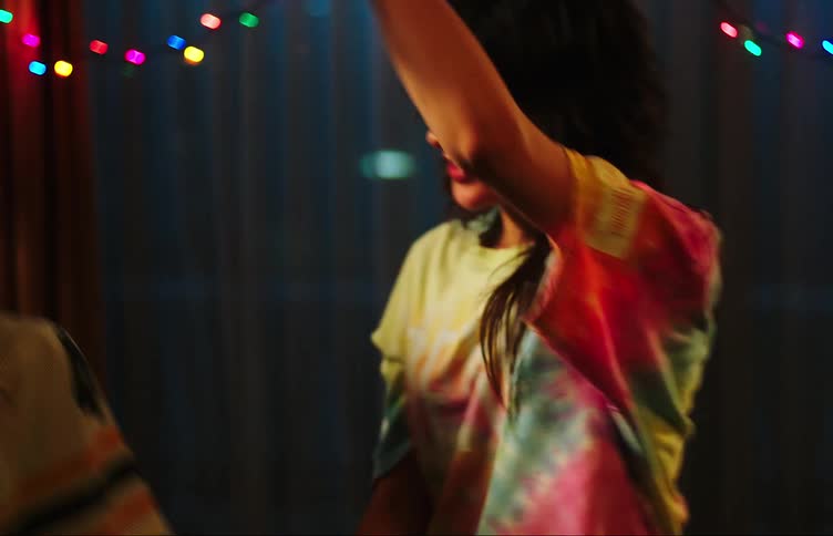 Two young women smile while dancing in room at night