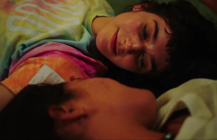 Two young women lying on the floor together head to head talking smiling and caressing each others heads