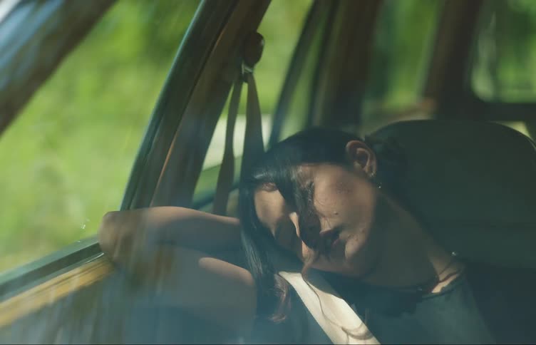 A young woman in a car sleeping in the passengers seat