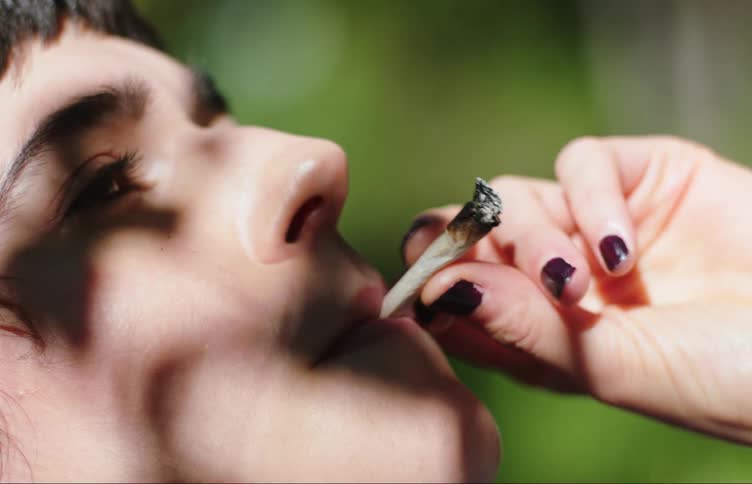 A woman is smoking a joint outside
