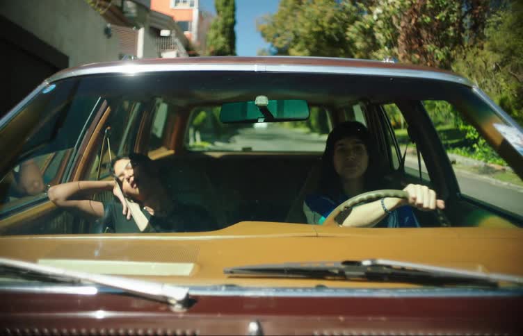 Front view of the windshield of a car with a woman driving and next to her another young woman sleeping