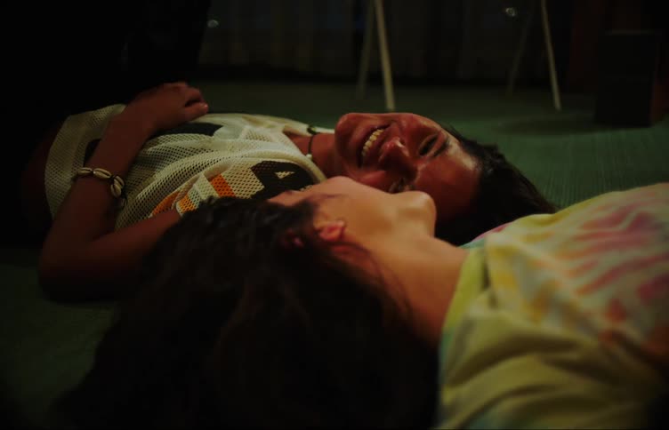 Two teenage girls laughing and talking on the living room floor