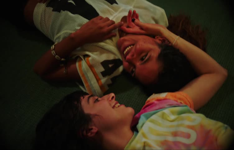 Two young women lying on the floor and looking at each other and talking to each other