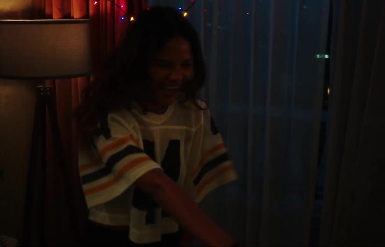 A young woman dances in a room at night