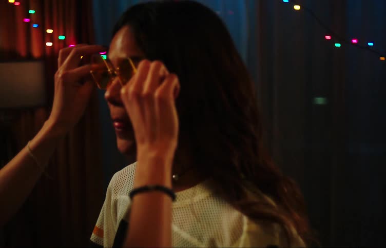 A girl takes a pair of glasses and puts them on another girl and starts jumping with joy