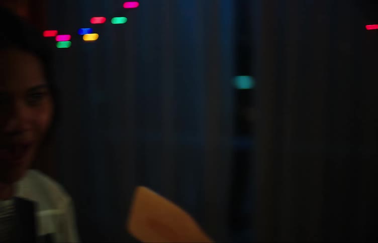 A young woman at a party sings with gusto into a hairbrush pretending its a microphone