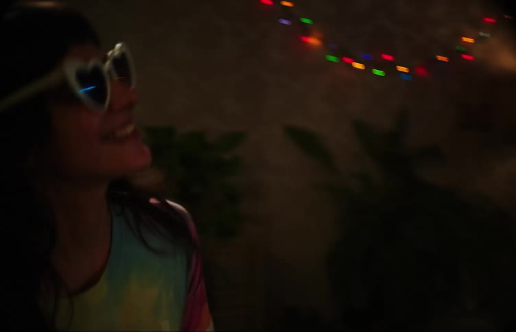 Two teenage girls dancing in a dimly lit room with colorful lights