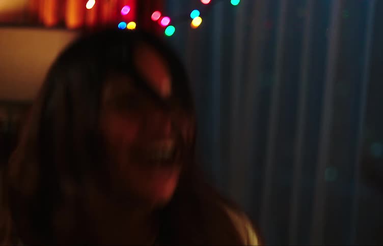 Two teenage girls dancing in a dimly lit room with colorful lights
