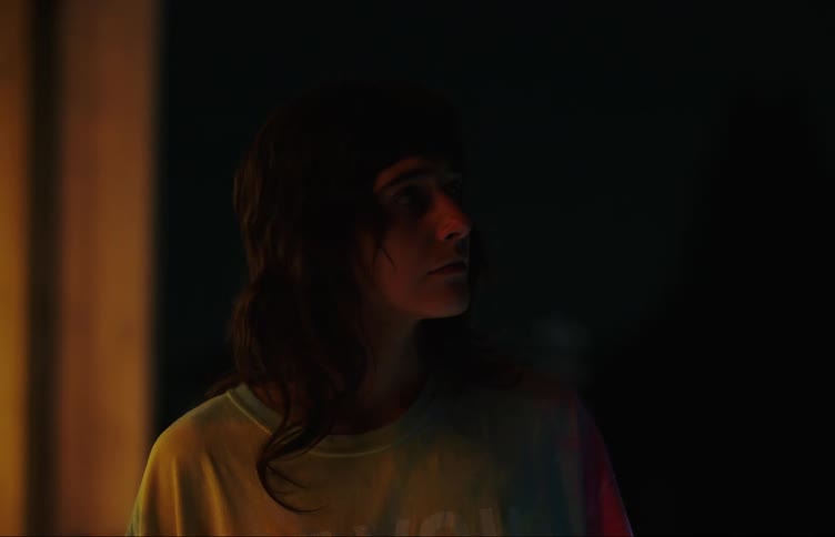 Young woman thinks while standing near window at night