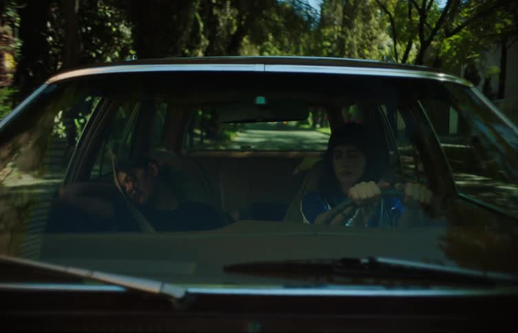 Two young women in a car one driving and the other sleeping on the passenger seat