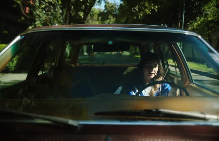 External view of the windshield of a car with a woman driving and another woman next to her in the passenger seat sleeping