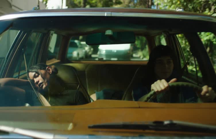 Woman driving a car on an urban road with a sleeping girl next to her