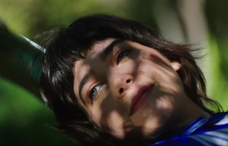 Close up of the face of a young woman relaxing over the hood of a car