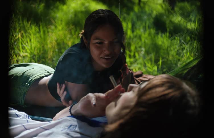 Two young women smoking on the hood of a car