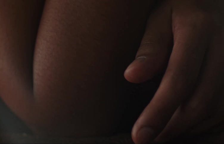A hand of a person with dark skin resting on their own arm