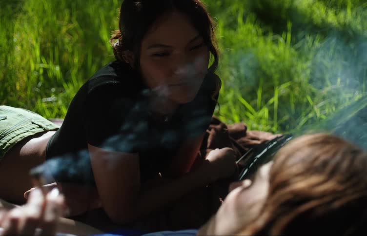 Two young women on the hood of a vehicle one smoking