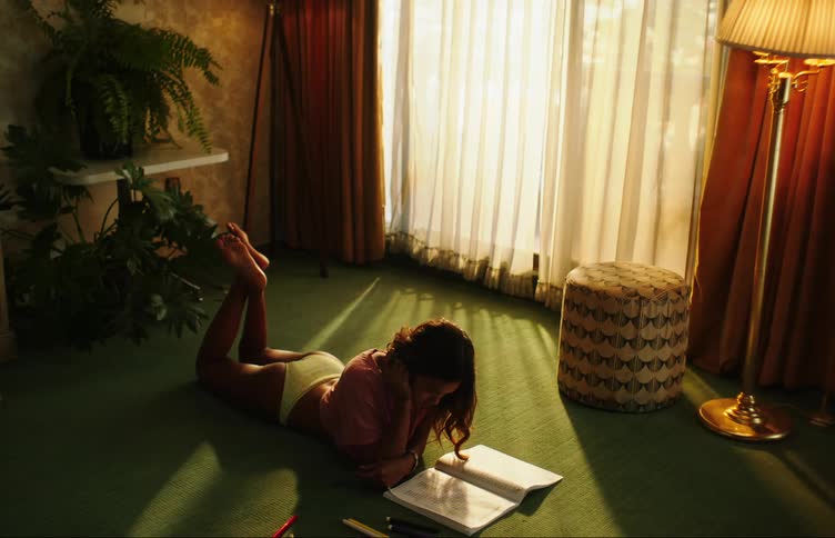 Woman lying face down in underwear on the carpet while painting a book