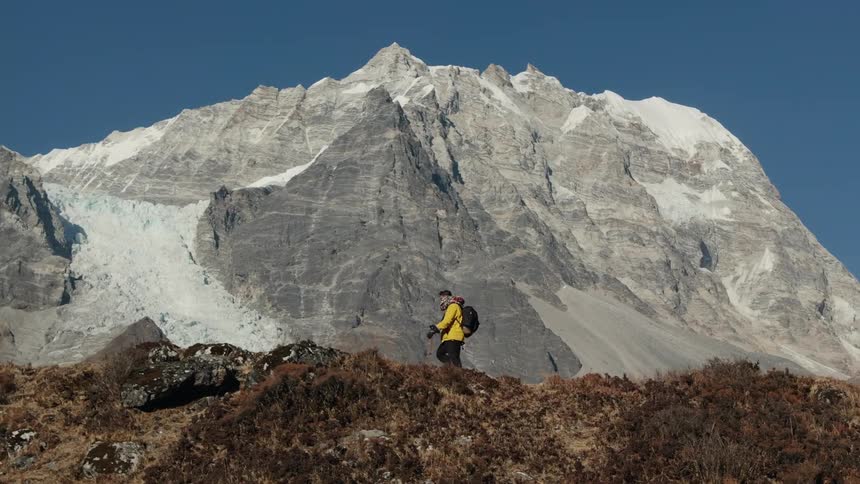 Man hiking on a cliff surrounded by rocky mountains in winter