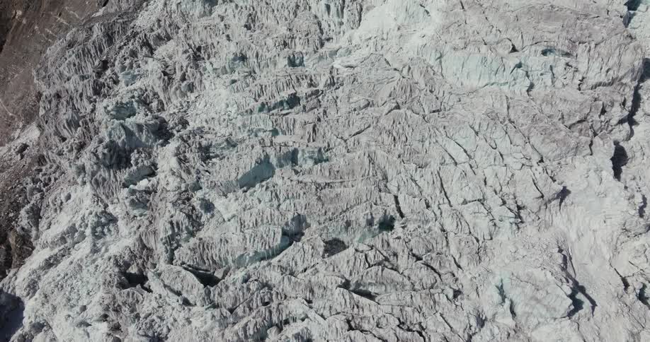 Aerial scenery with downward view of cracks and geological deformities in snowy mountains