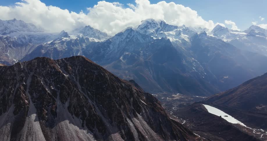 Aerial scenery of rocky mountain range in winter with snow and clouds around