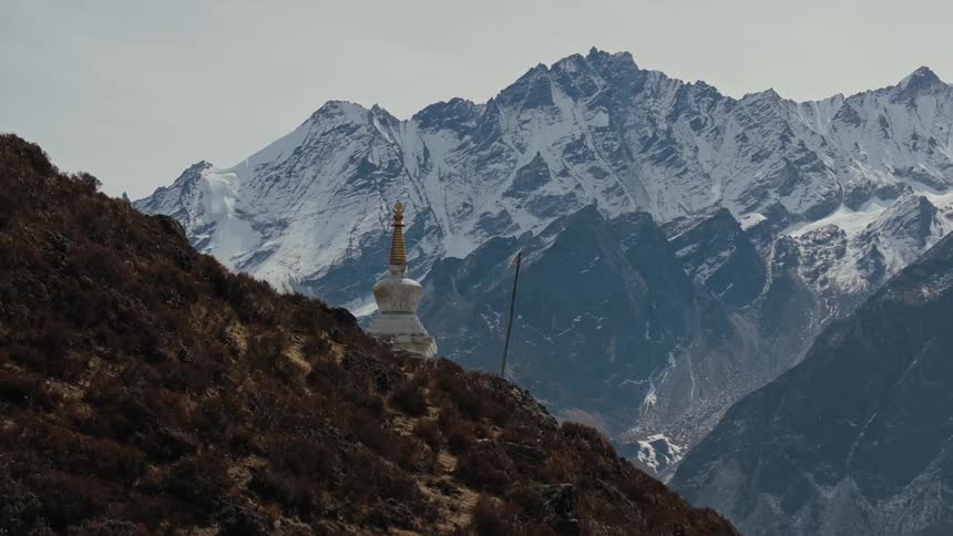 Aerial scene of a temple on a hill with snowy mountains around