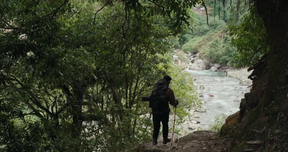 Man with hiking equipment walking along a mountain by a river