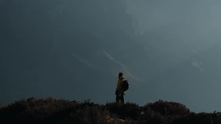 Man with hiking equipment on a cliff with big mountains around him