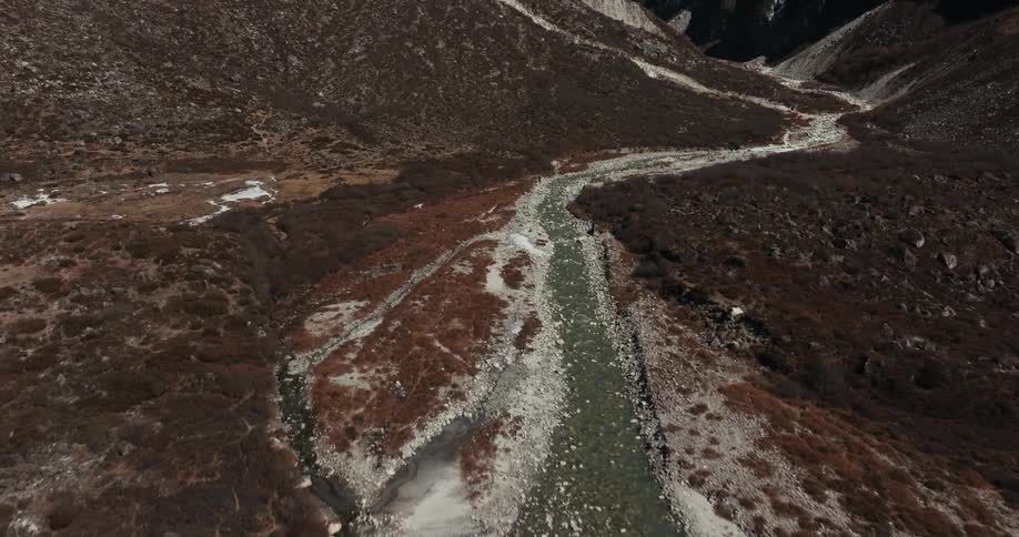 The cameral follows a flowing river to reveal a mountain pass