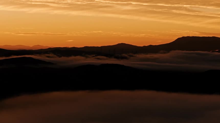 Mountains and hills stand silhouetted against red sky after dusk