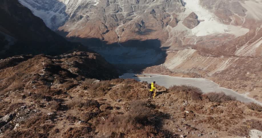 Man hiking in a natural and geological environment surrounded by large mountains