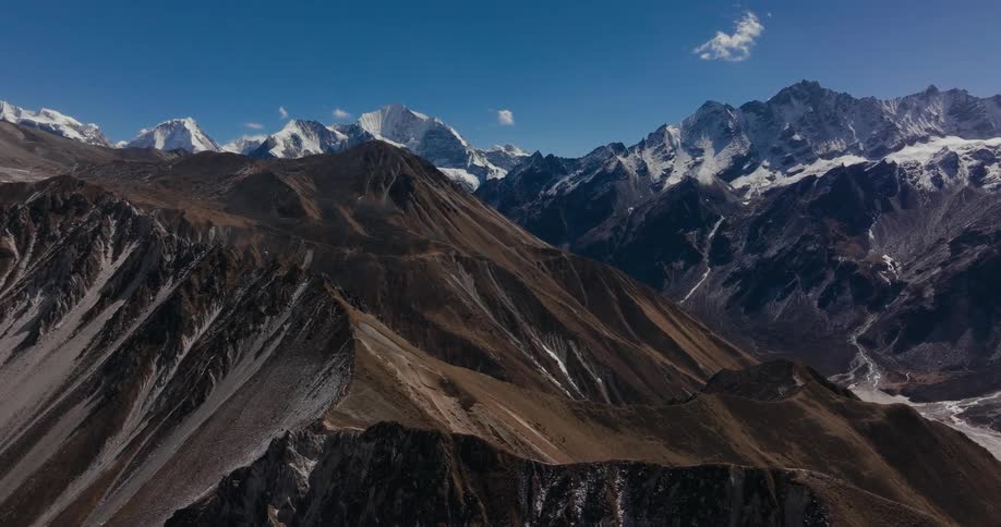 Aerial view of the barren slopes of a mountain range under a blue sky