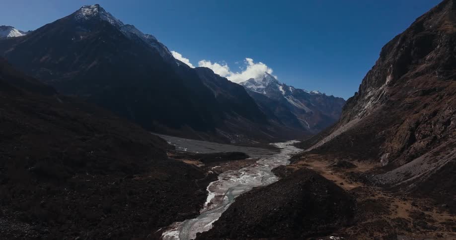 A large and narrow river in the middle of mountain ranges on a cloudless blue sky day