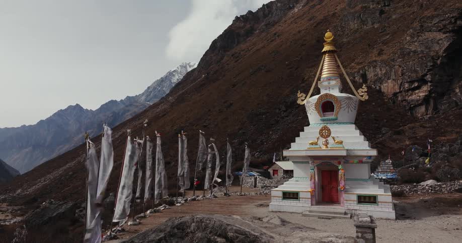 Buddhist temple on a hill surrounded by mountains on a cloudy day
