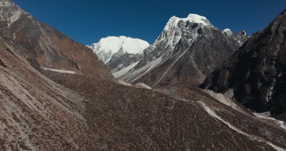 Aerial scenery of snowy hills and mountains and cliffs on a cloudless blue sky day