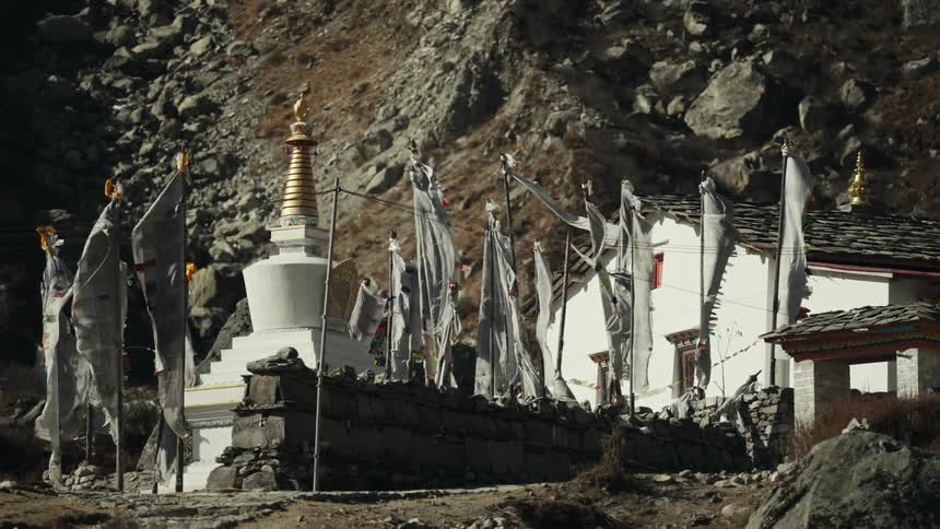 Several white flags moving due to the wind near an old building