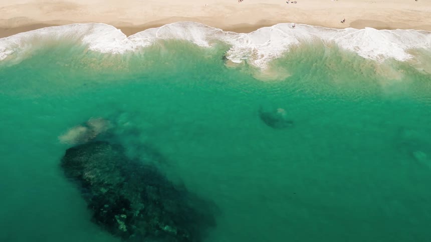 Aerial view of waves gently crashing on a beach