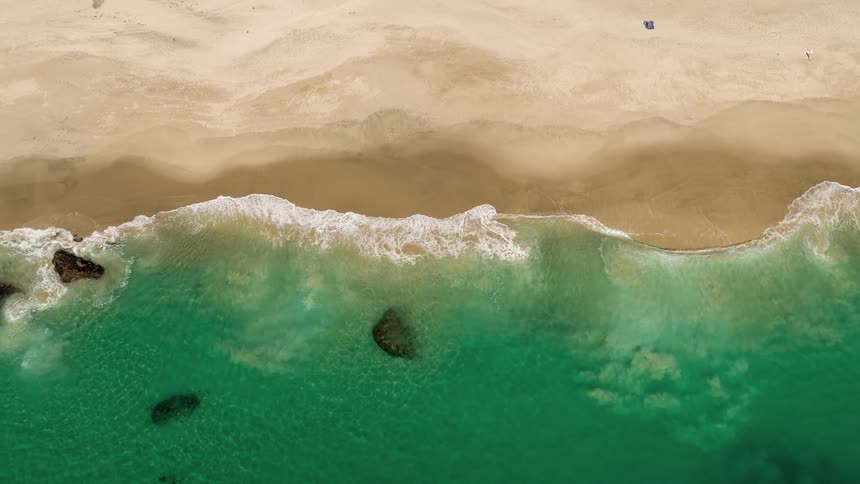 Aerial view of waves gently crashing on a beach