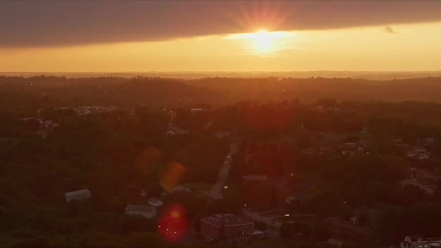 Aerial panorama of a residential city built on hills and sunrise and radiating strong on the horizon
