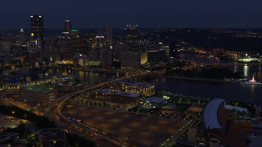 Aerial panorama of a seaside metropolis illuminated at night with skyscraper buildings and sports stadiums