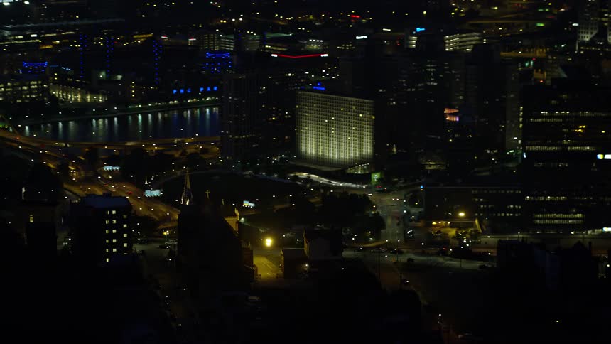Aerial panorama of a metropolis with large buildings illuminated at night with streets with vehicle traffic and sea canals